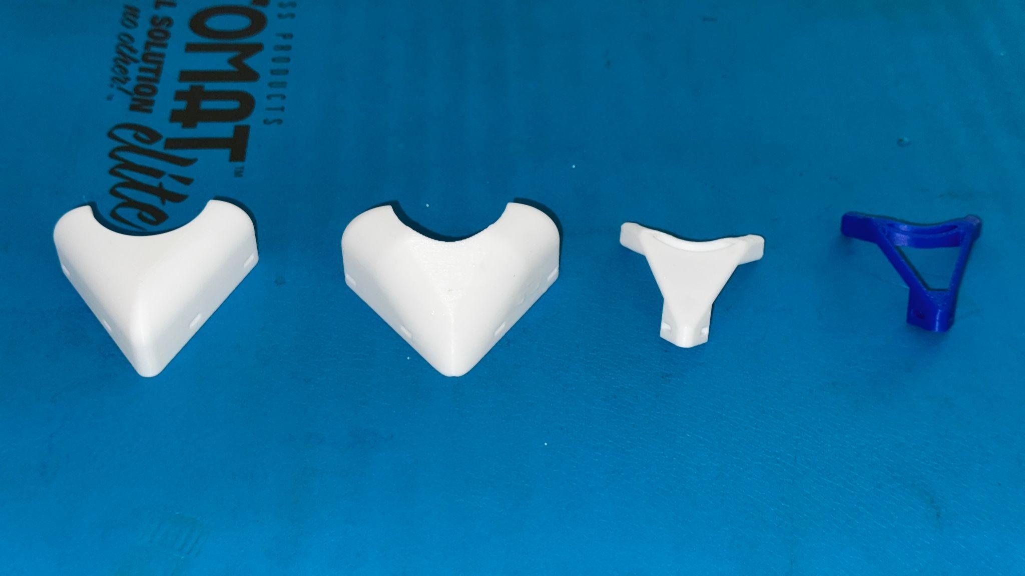 Four different printed nose guard prototypes arranged on a blue work surface